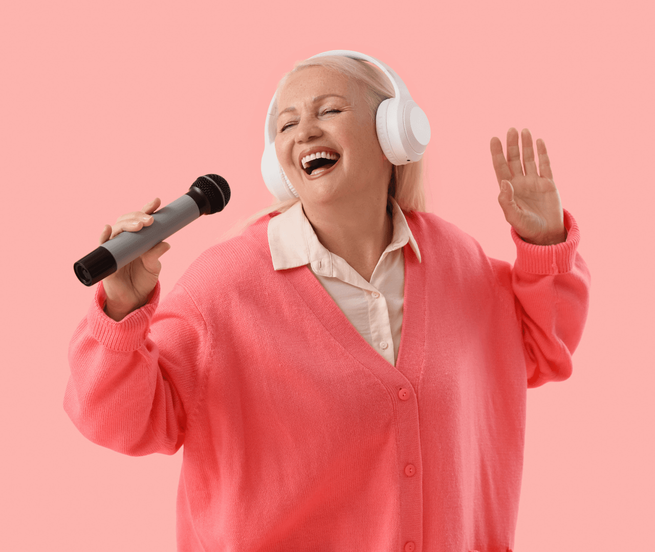 A woman in pink singing with headphones and a microphone.
